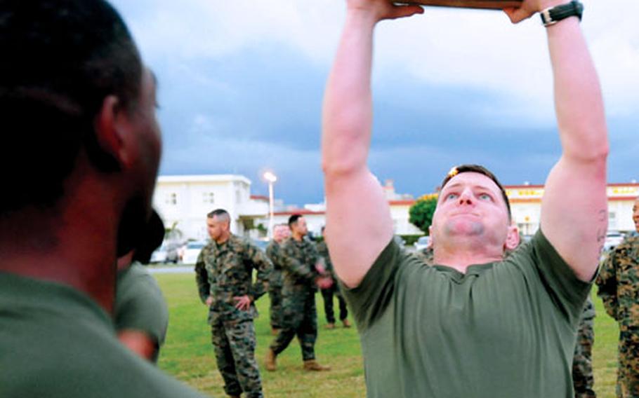 Marine Corps Warrant Officer Justin Hays lifts a 30-pound ammunition can over his head during the ammunition-can lift portion of the combat fitness test on Camp Foster, Okinawa.