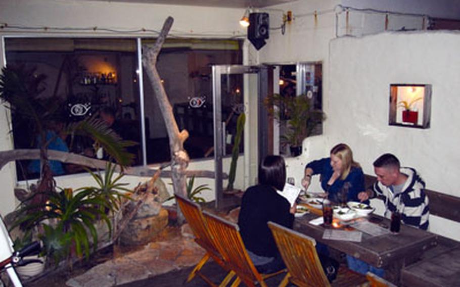 Me Kara Uroko on the Sunabe Seawall in Okinawa has an outdoor eating area decorated with driftwood, as well as indoor seating and a bar serving an extensive selection of drinks.