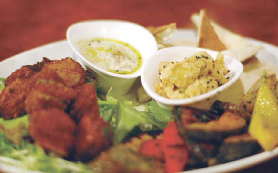 The vegetable plate at Addis Restaurant and Cafe in Tokyo includes, clockwise from left, falafel, baba ghanoush, hummus, pita triangles, and grilled peppers, pumpkin, mushrooms, eggplant and zucchini. The restaurant is named for the capital of the owner’s native Ethiopia and has an eclectic cuisine.