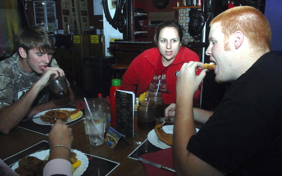 From left, Americans Dalton Moon, Alicia Barnes and Andrew Goins enjoy some fried food at Angelo's Soul Food Joint. The restaurant is run by a former Army NCO who says he cooks the same way his family in North Carolina does.