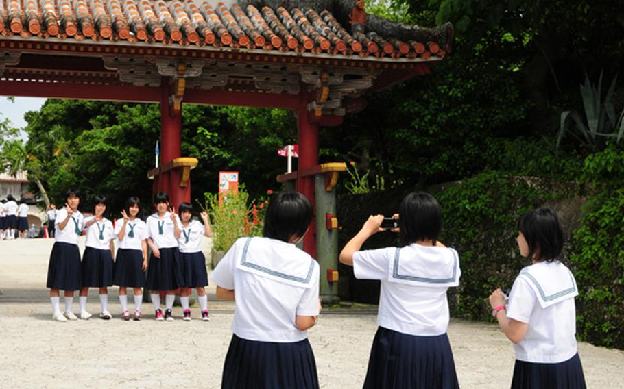 Some Japanese school children on a tour of the castle grounds stop for a quick photo under the Shureimon Gate, the main entrance to the Shurijo Castle Park.