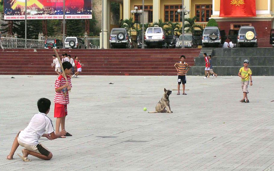 On the public square in Dien Bien Phu, Vietnam, local boys play baseball. Nong Duc Anh, 10, has just thrown the ball and Dang Quang Anh, 12, is reaching for the catch.