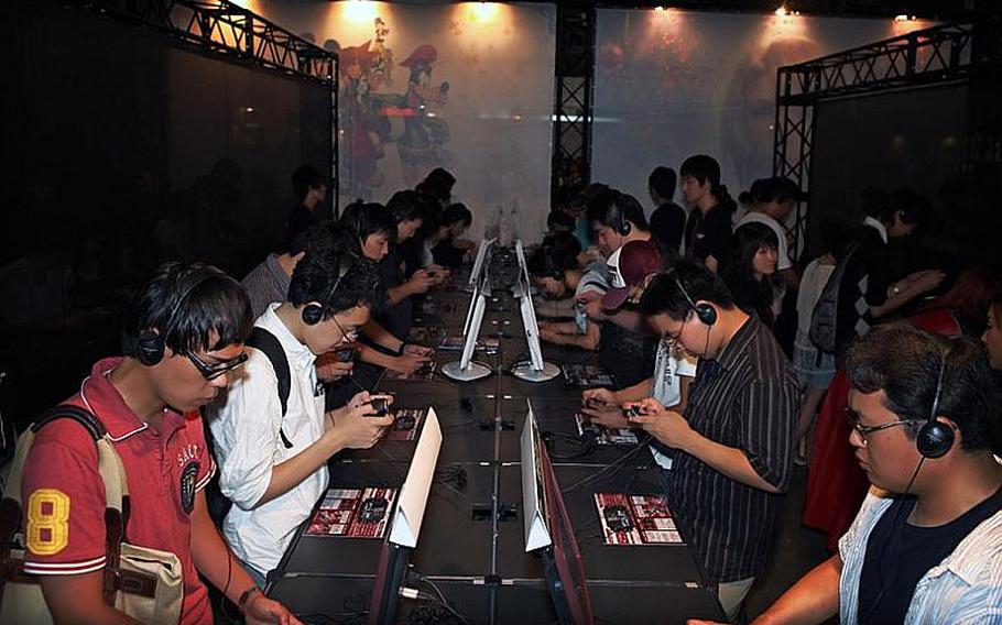 Visitors try out some new video games at the Tokyo Game Show 2010 at Chiba Prefecture's Makuhari Messe convention center on Saturday.