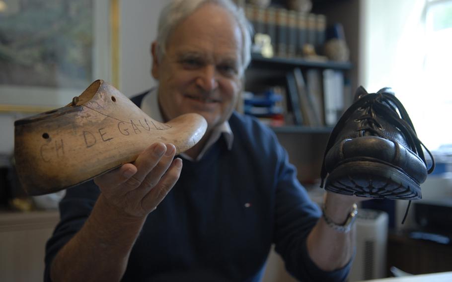 Willy Schächter, director of the German shoe museum in Hauenstein, Germany, holds up the wooden shoe mold for former French statesman Charles de Gaulle and a walking shoe once belonging to former German Chancellor Helmut Kohl.