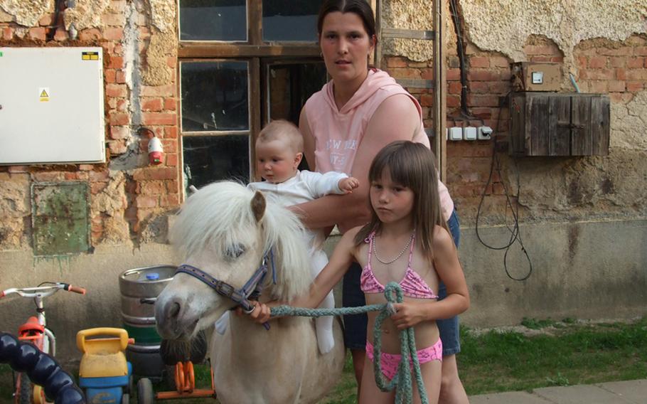 Michaela Kodadová, who helps run the Svrzno stables and a small pension near Hostoun, Czech Republic, helps her two daughters get used to being around horses.