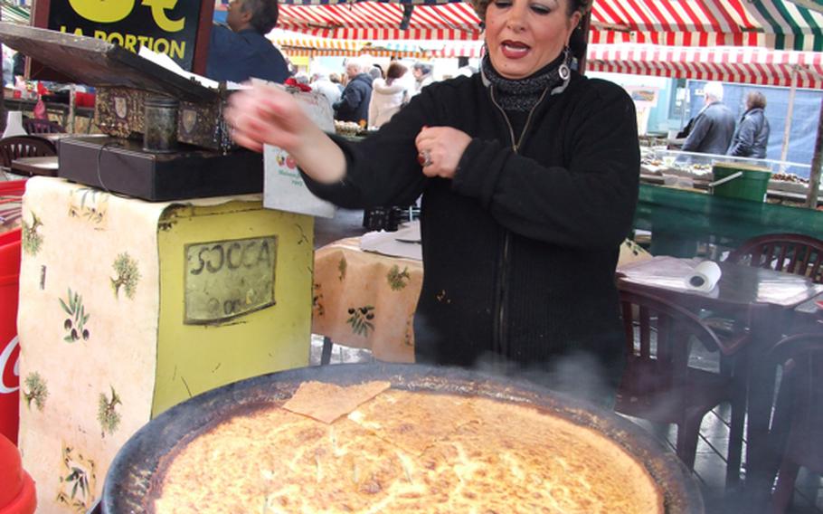 Theresa sells socca, a giant crepe made with chick pea flour and  cooked on a wood-burning stove, at the city  market in Nice, France. The stand is an institution in the city and Theresa is happy to pose for photos.