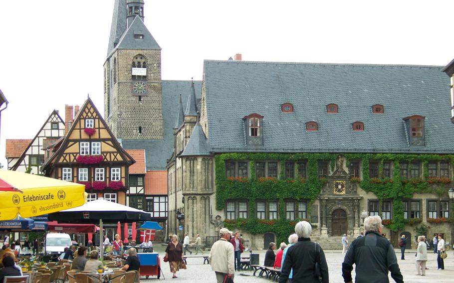 The market square in the old town of Quedlinburg, Germany, gets busy in the afternoon, as residents and tourists alike gather to relax at an outdoor cafe or stroll amid the medieval architecture that borders the huge square. Dominating one side of the square is the vine-covered city hall. In the background is the Church of St. Benedikt.