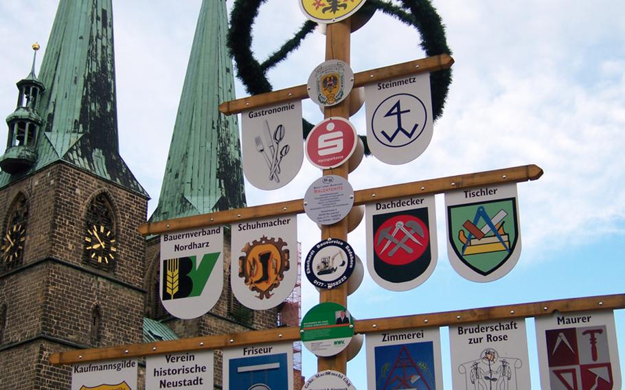 Past and present come together in this 'advertising tree' found on a small square in Quedlinburg. Modern advertising runs down the center of the pole while shields dangling from the crossbars depict skills and trades from the town's past. Among the trades the shields advertise are: a stone mason (Steinmetz), carpenter (Zimmerei), roofer (Dachdecker) and cobbler (Schuhmacher).