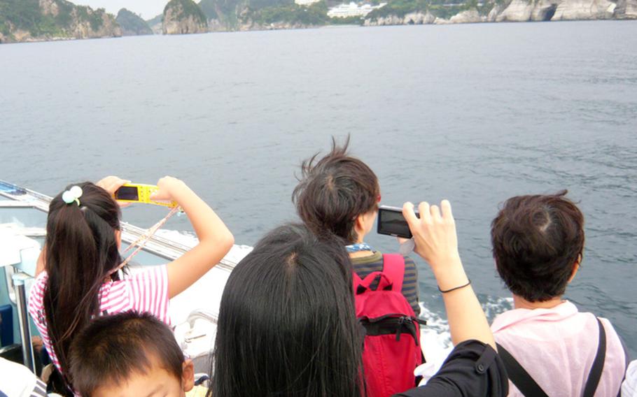 Tourists on a boat at Dogashima take photos of the islands.