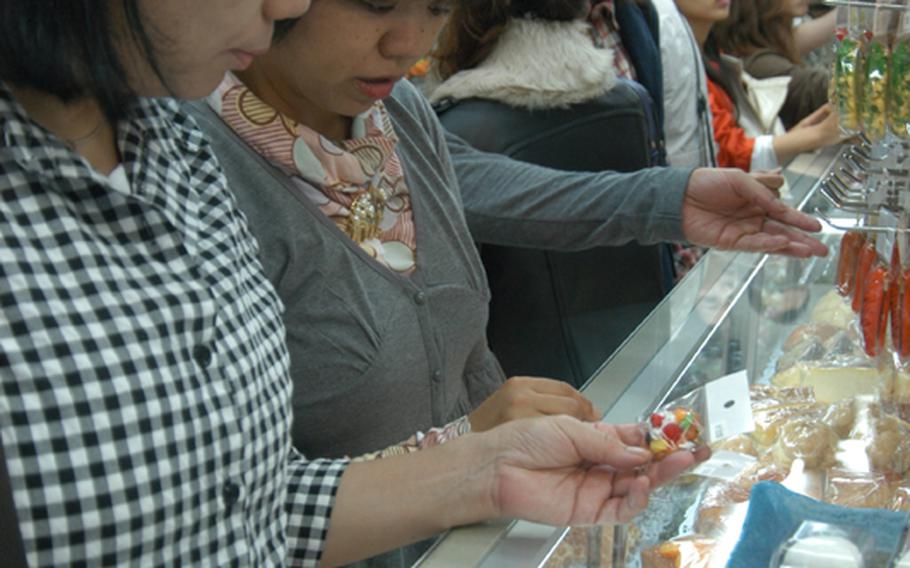 Shoppers look at plastic food cell phone charms. Sushi, cakes and donuts are among some of the various types of charms sold at stores in Kappabashi.