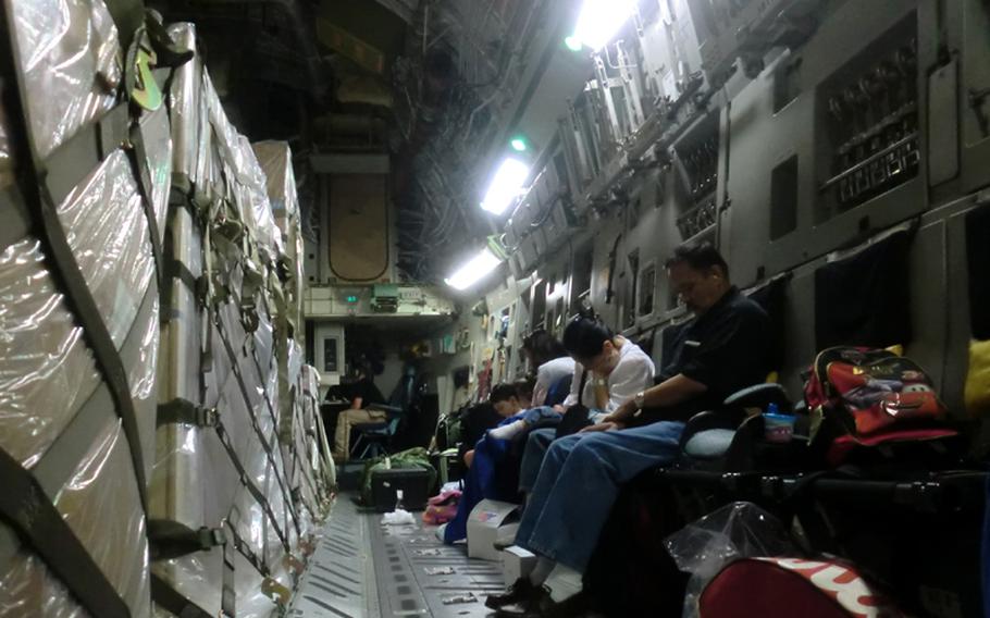 Sharing the space with pallets full of equipment, Space-A passengers rest aboard a C-17 aircraft bound for the U.S. from Japan.