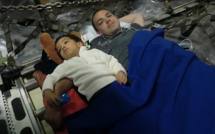 Space-A passengers Tim Wightman and son, Dallin, relax on the floor inside a C-130 aircraft bound for the U.S. from Japan.