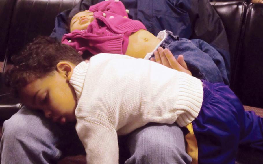 Tim Wightman supports his sleeping children while trying to grab some shut-eye for himself during a layover in Anchorage, Alaska, part of his family's space-A trip from Seattle to Japan on the Patriot Express.
