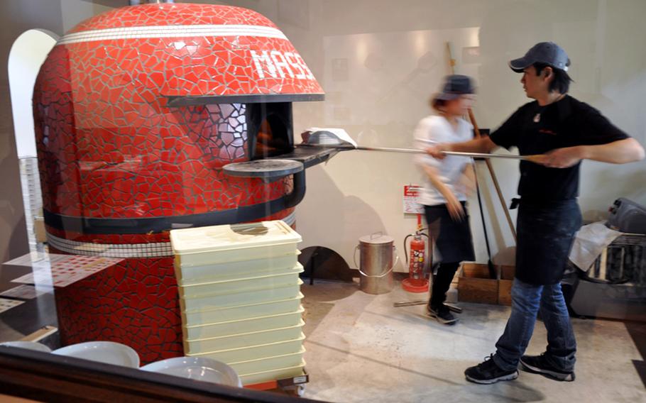 An employee slides a pizza into the imported Italian stone pizza oven at Pizzeria Massimo in Misawa city, Japan.