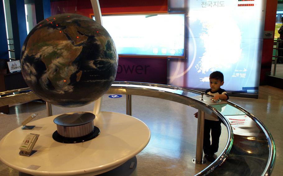 Diego Jimenez, 3, pushes a button on an interactive display that demonstrates wireless power transmission at the Gwacheon National Science Museum in Seoul, South Korea.