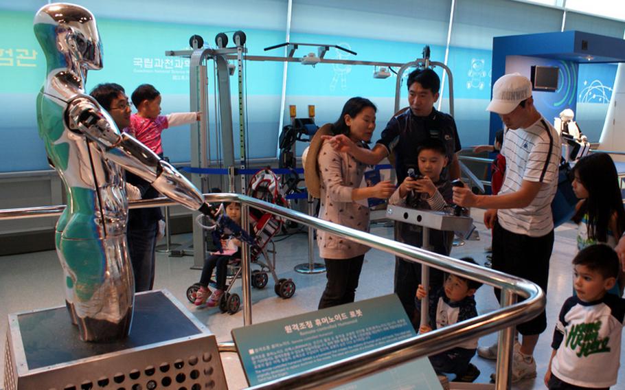 Visitors use a remote control to test a robot's movements at the Advanced Science & Technology Hall at the Gwacheon National Science Museum in Seoul, South Korea.