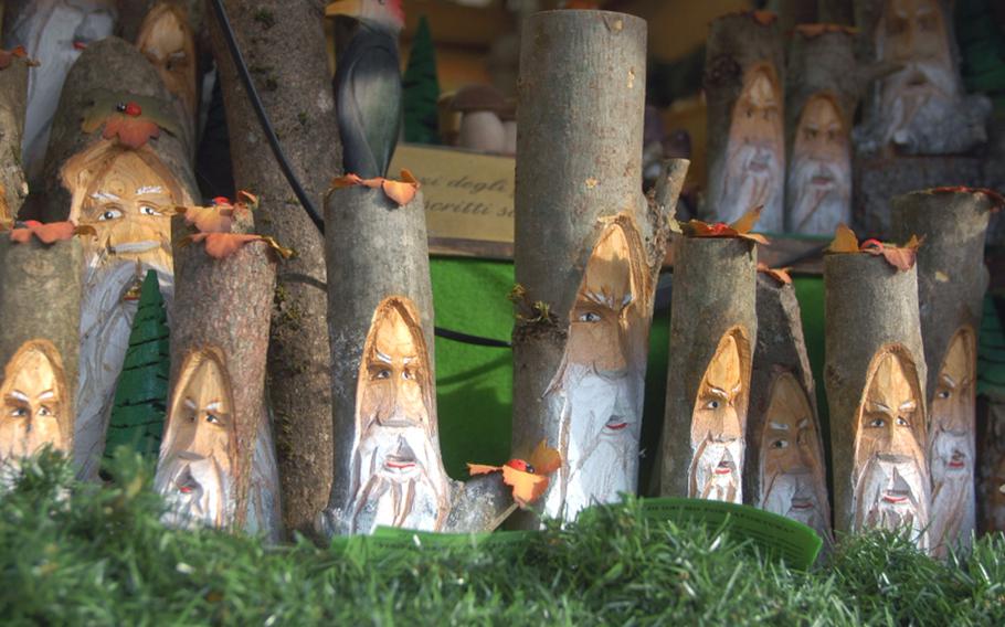 Decorative gnomes carved from a tree branch stare out from a booth at the Christmas market in Trento, Italy.