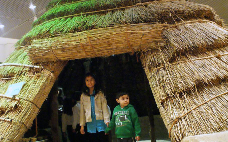 Natalya and Diego Jimenez stand under a hut during a visit to the Children's Museum at the National Museum of Korea. The museum gives children a hands-on experience by letting them handle tools and puzzles indicative of ancient South Korea.