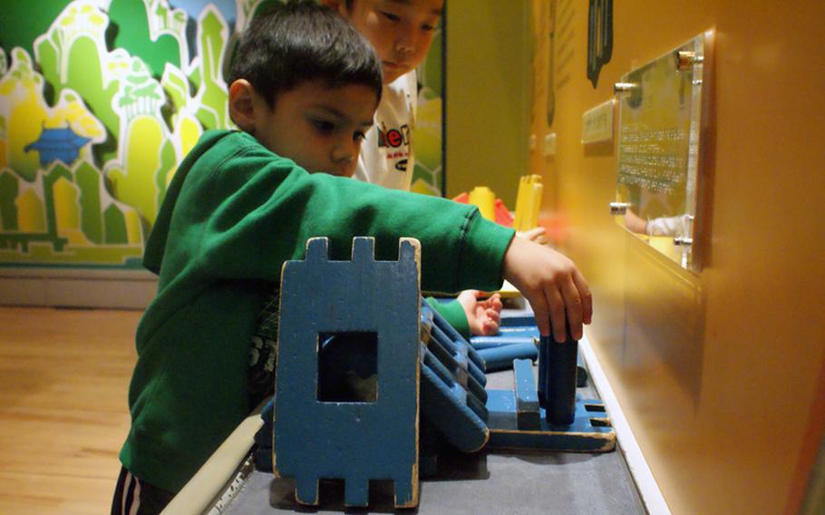 Diego Jimenez gets assistance building a house out of blocks during a Nov. 22 visit to the Children's Museum at the National Museum of Korea. The museum gives children a hands-on experience by letting them handle tools, puzzles and pots found in medieval South Korea.