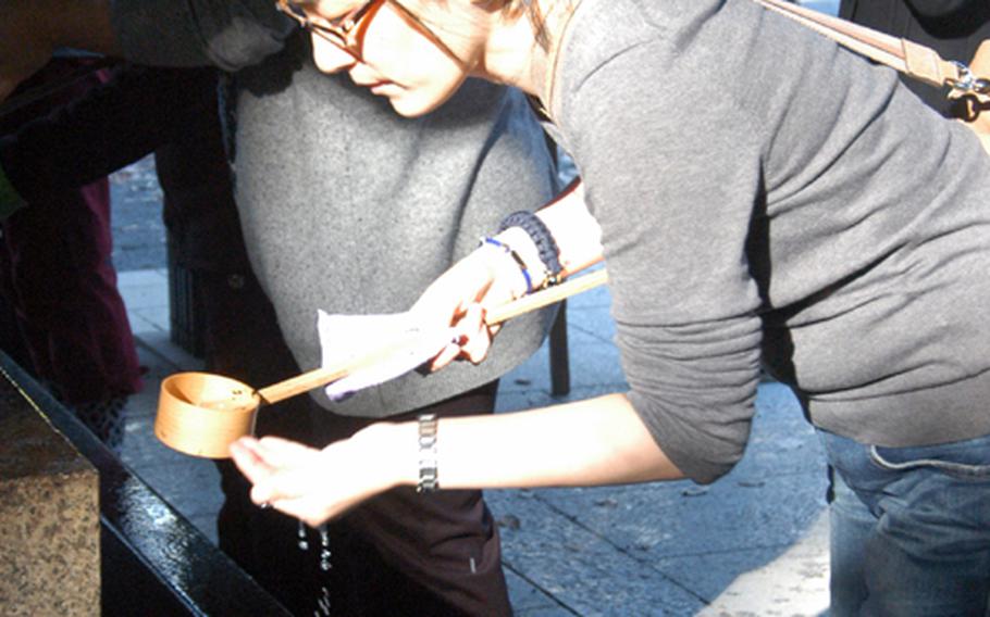 A visitor at Meiji Jingu washes her hands at the water basin before entering the altar. Worshippers are expected to wash their hands and mouths before entering the altar to pray in order to cleanse themselves.