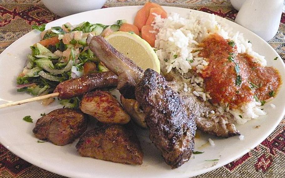 The Brochettes Casbah from Al Casbah in Cambridge, England, is a mixed grill plate with lamb and chicken medallions, a lamb chop, spicy merguez sausage and kafta served with a fresh vegetable salad and rice with tomato sauce.