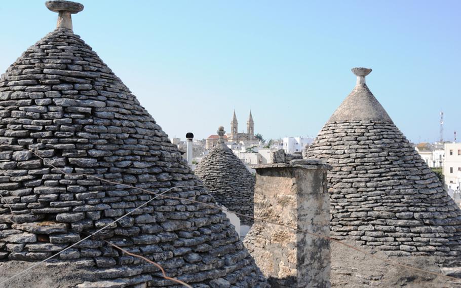 Rooftop panoramic view of some of the fieldstone, cone-shaped roofs and chimneys of the famed trulli houses of Alberobello.