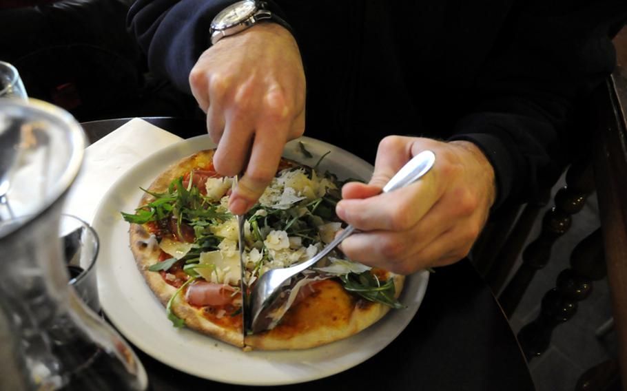 A customer cuts into his pizza topped with ham, arugula and Parmesan cheese at Pizzeria Il Pomodoro in downtown Stuttgart. He described the pizza as "fantabulous."
