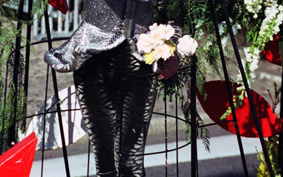 A costumed participant in Nice&#39;s Bataille de Fleurs carnival parade throws a bouquet of flowers to the spectators. 