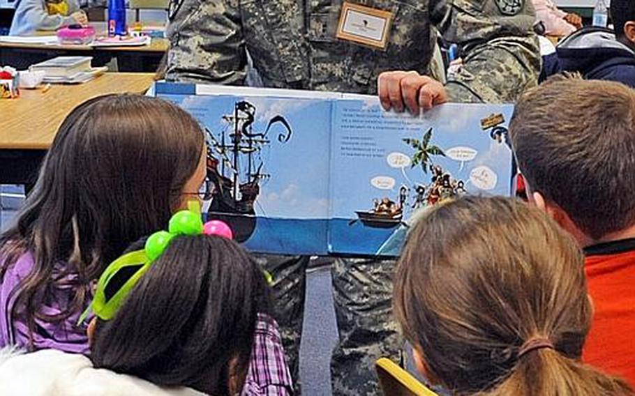 Chief Warrant Officer 2 Mark Morton of the Wiesbaden, Germany, branch of the CID, shows Hainerberg Elementary School pupils the pictures in "The Pirate Cruncher," the book he read to them for Read Across America Day. Morton said had he remembered that the book included singing, he would have brought another book. The kids however, enjoyed his rendition.
