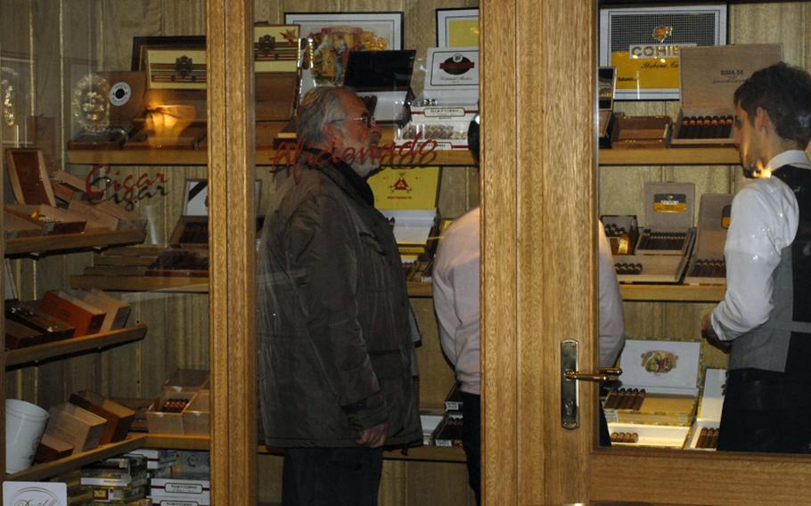 Guests at the Cigar Bar Lounge in Frankfurt, Germany, look over the bar&#39;s selection of premium cigars from the Dominican Republic, Honduras and Cuba.  The lounge&#39;s temperature and humidity controlled walk-in humidor houses cigars at many different price points.