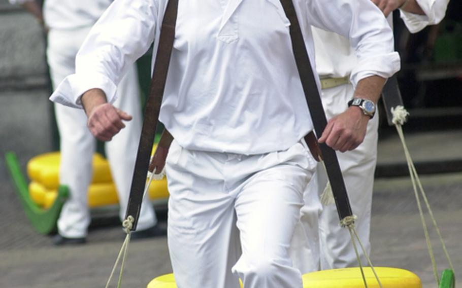 A team from the cheese carriers guild,  carry wheels of cheese across the Waagplein, after they were weighed during the Friday cheese market in Alkmaar, Netherlands.