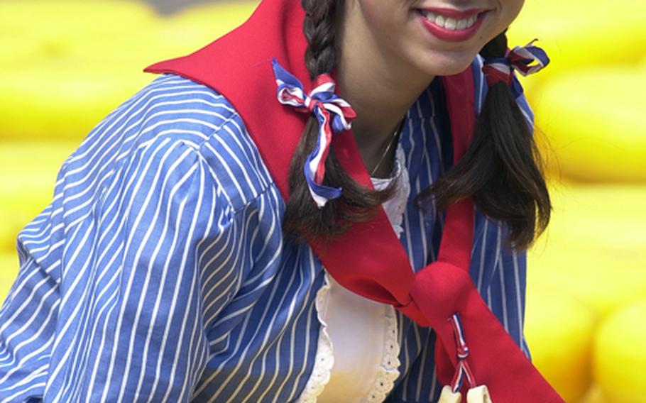 A young woman dressed in traditional Dutch style holds a wheel of cheese at the Alkmaar cheese market.