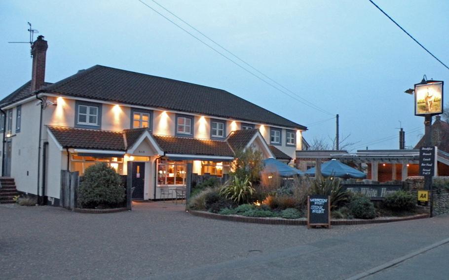 The exterior of The White Horse in Brancaster Staithe is illuminated by electric lights as the light of day comes to an end in late March. The establishment offers a restaurant, pub and inn along the coast in northern Norfolk.
