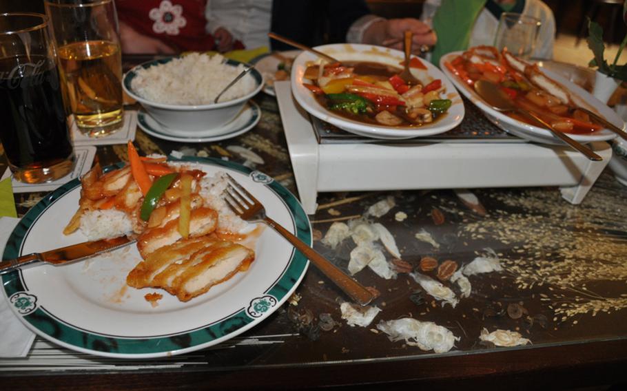 A plate of sweet-and-sour chicken, with the chicken leftovers, along with a shrimp-and-vegetable dish, kept warm on a mini heater. Both dishes on the lunch menu cost about 7 euros.