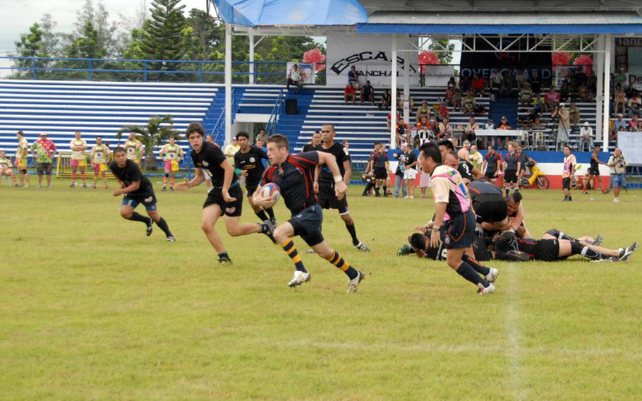 Petty Officer 3rd Class Mike Kaltsunas sprints away from defenders during a rugby match last September while in port in the Philippines.