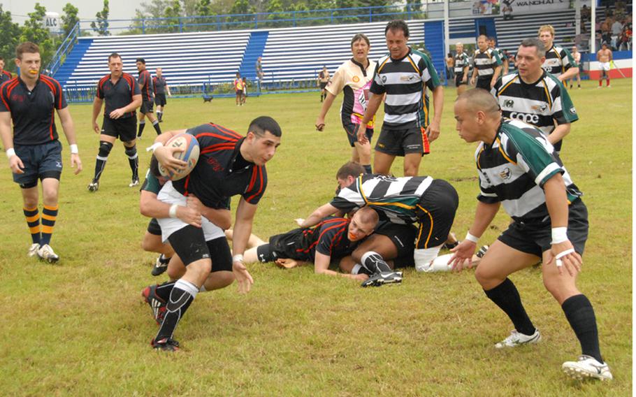 Navy Airman Andrew Matyas gets tackled as he runs with the ball during a rugby match last September while in port in the Philippines
