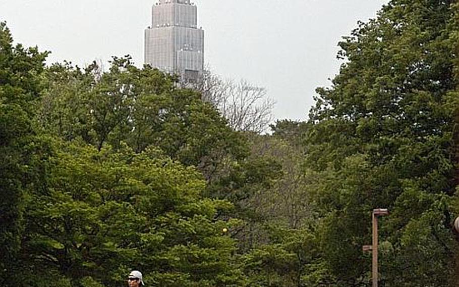 A couple plays catch while other visitors relax on a Saturday at Yoyogi Park in Tokyo.