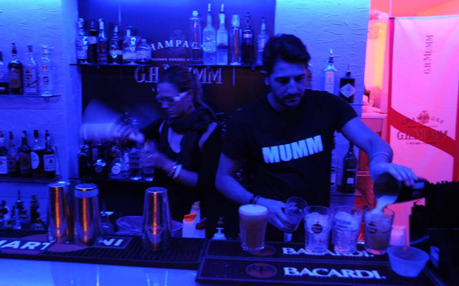 Bartenders mix up a variety of cocktails at G.H. Mumm in the port area of Pozzuoli, a suburb of Naples. The pub is down a narrow alley instead of in the middle of a piazza, one of the pub&'s alluring features.