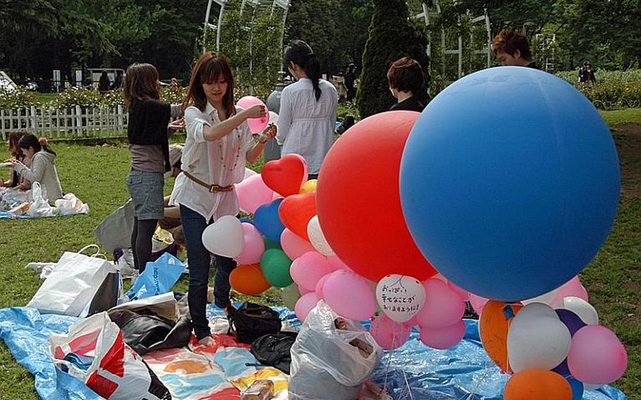 A woman adds a balloon to what is already a large arrangement at Yoyogi Park in Tokyo.