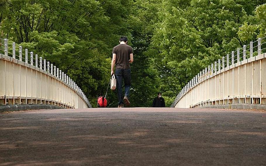 A visitor to Yoyogi Park and his dog cross the bridge from one side of the park to the other on a Saturday afternoon.