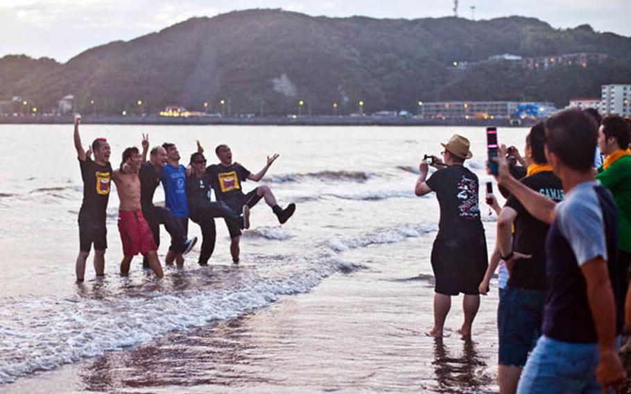 A performance comedy group poses for photos after running into the ocean at Zushi Beach following their show at Otodama Sea Studio on July 9.