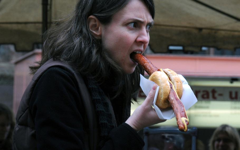 A woman in Freiburg's market square bites into one of the city's specialties, a spicy bratwurst.