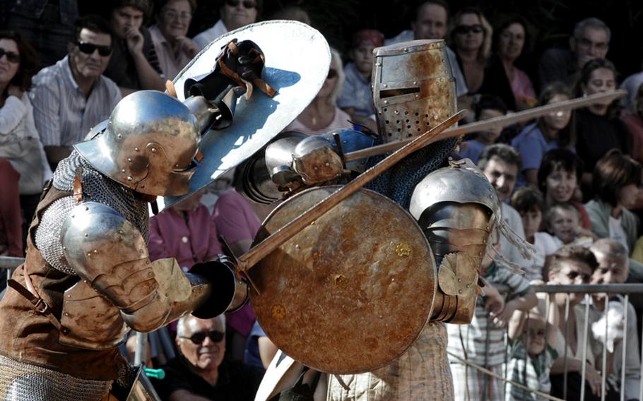 Knights wielding swords and shields clash during the fest as a crowd gathers to watch.