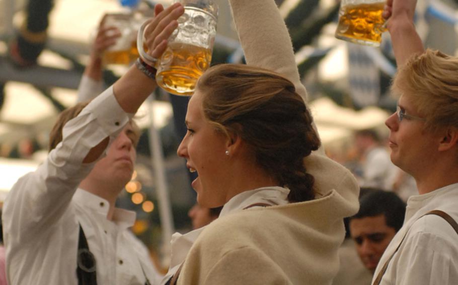 Wearing typical Bavarian dress, friends toast each other.