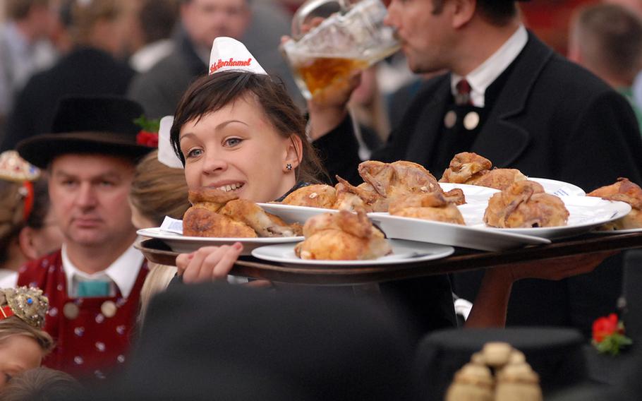 A server with a tray of chicken makes her way through the crowd in the Schottenhamel tent. Halves of chicken are popular at the festival, as are ham hocks, duck, pork roast and, of course, sausages.