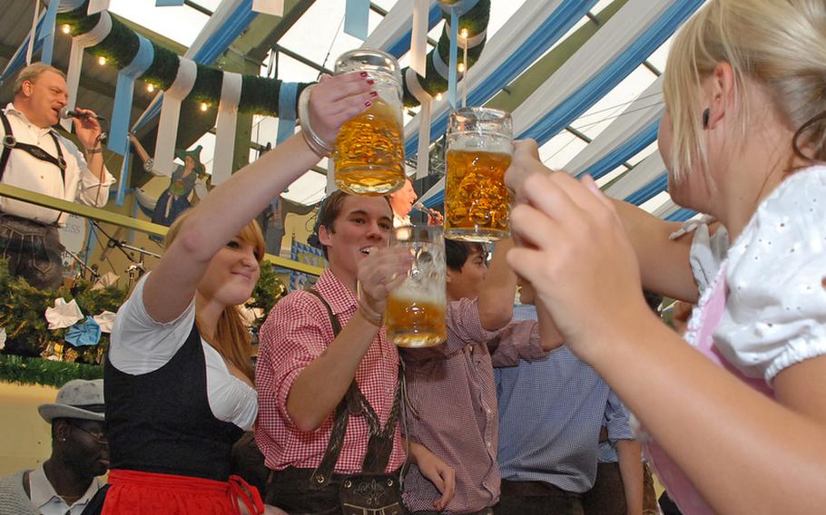 Dressed in typical Bavarian dress, friends toast each other with liter mugs of beer.