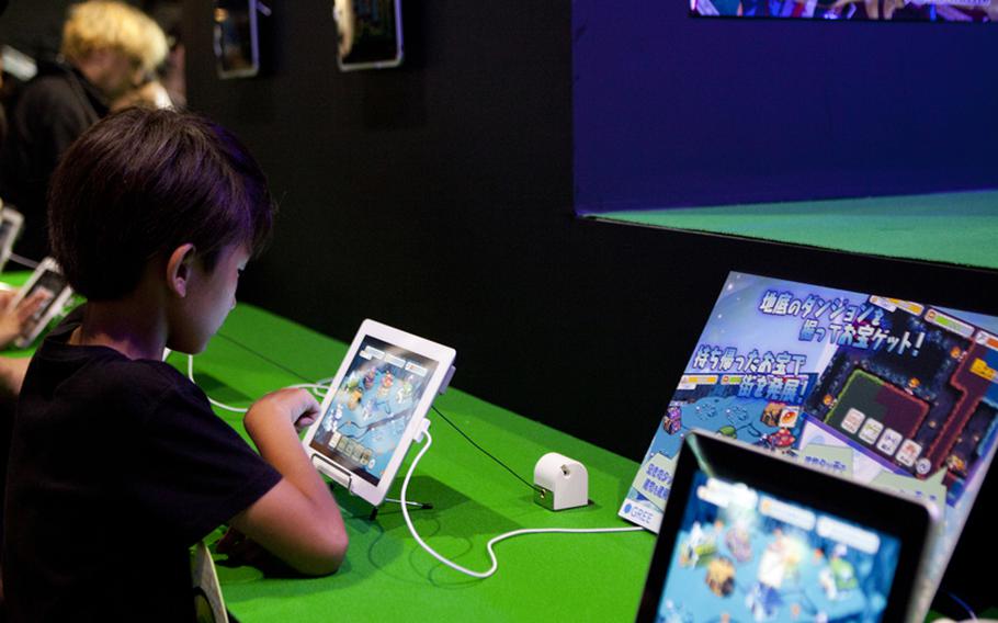 A young gamer tries out one of the many new titles on display for the Apple iPad, some of the many new titles on display" Saturday at this year's Tokyo Game Show held at Chiba Prefecture's Makuhari Messe convention center.