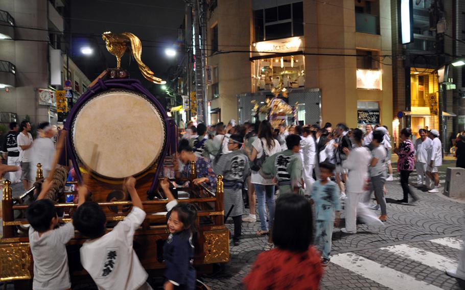 Children play with a drum while the adults move the shrine into its final position at the festival.