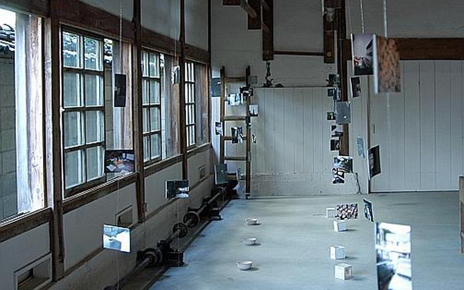 Photos depicting what the old Kozan Touen pottery factory compound and gardens have become, hang from the rafters in an art exhibit in one of the factory's old out-buildings. The building houses an art gallery and shop.