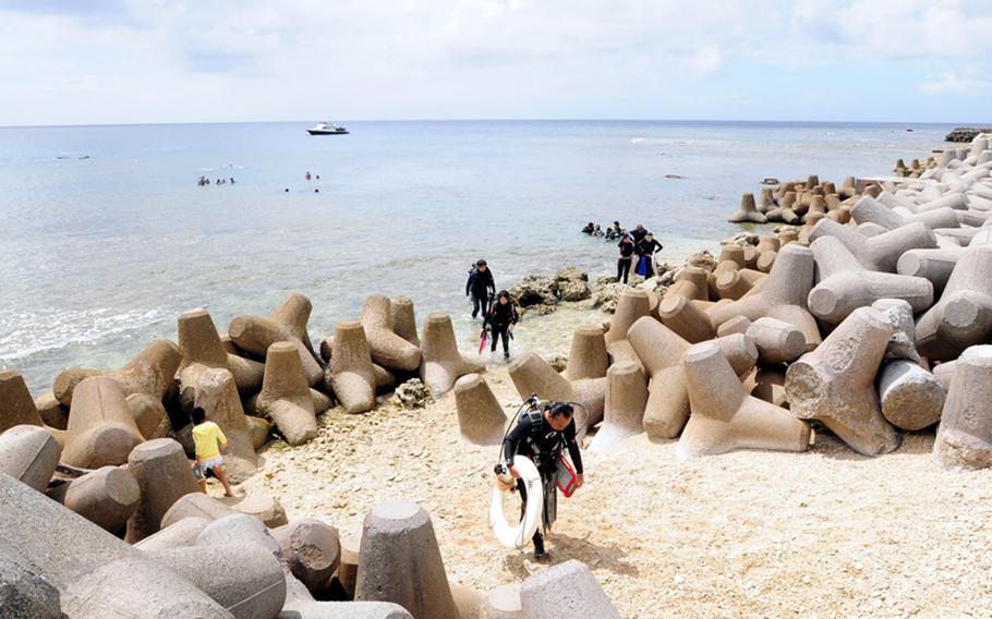 Scuba divers exit the water after a dive. The area has a wide diversity of hard and soft corals as well as a wide variety of fish to keep scuba divers entertained. During calm weather, the area sees a huge influx of scuba divers gearing up a heading into the water.